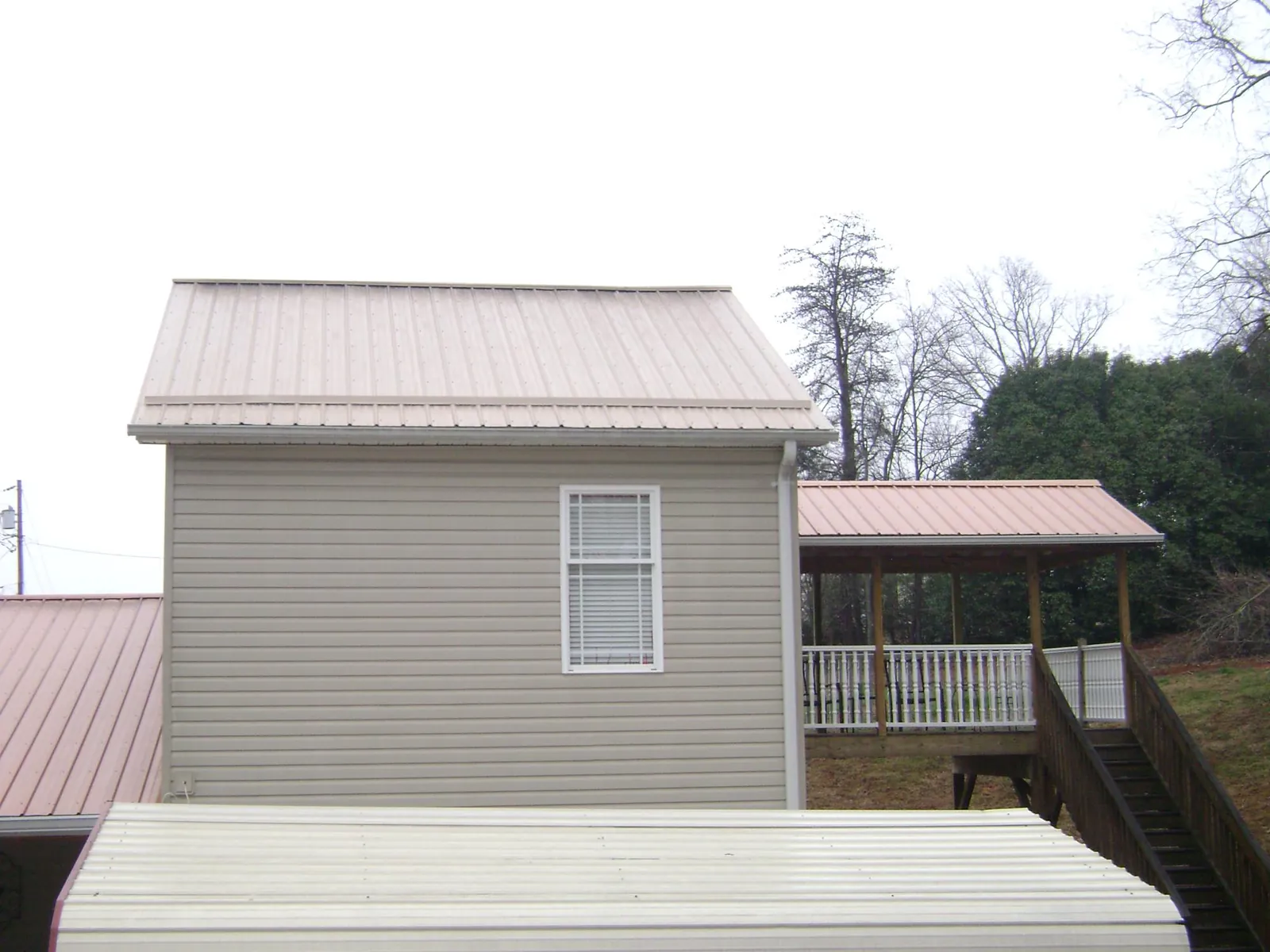 Tan metal roofs on a two story addition and attached porch, from a Roof Replacement job in Oxford